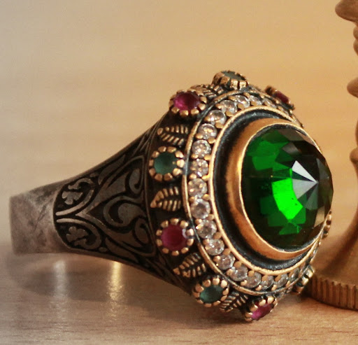 Anillo de oro con una piedra verde en el frontal.